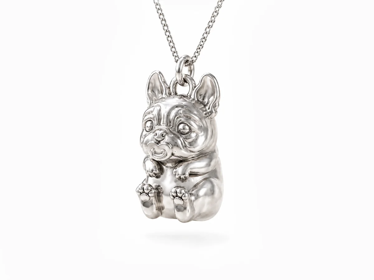 Angled view of a sterling silver French Bulldog pendant showing its detailed facial features, rounded body and polished metal surface